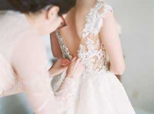 Back of brides wedding dress being buttoned up from wedding video