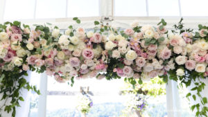 wedding ceremony arbor at with stunning white and pink flowers by the east side's best wedding videography